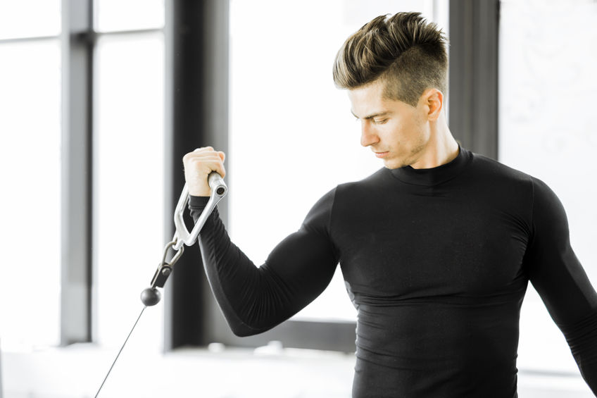 Young man doing bicep curls with cable weight